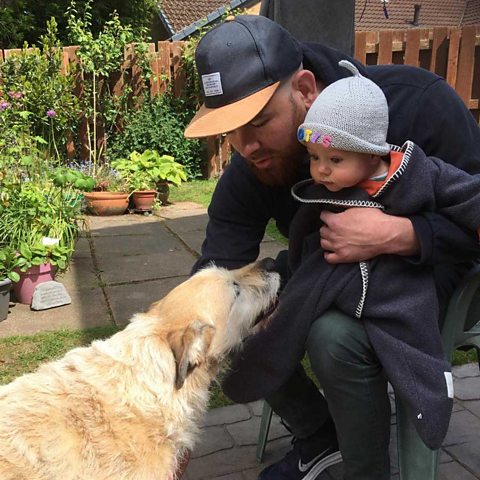 Tom and baby Otis greeting a dog.