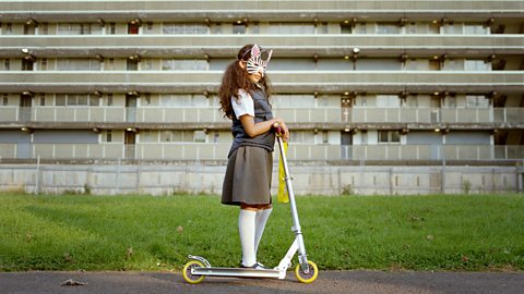 Girl with an animal mask on riding a scooter