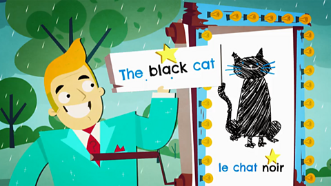 Burt standing in front of his display with 'le chat noir' on it. He's holding a sign with the black cat written on it.