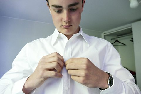 Young boy getting dressed for school
