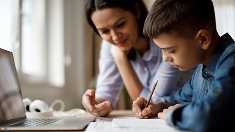 Mum helps her son with some schoolwork