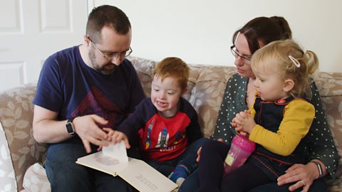 Family looking at book sat on sofa