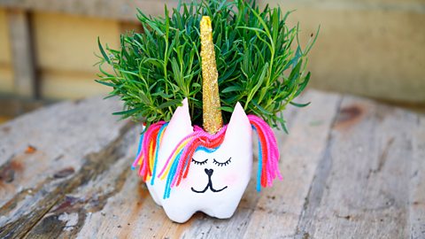 A unicorn animal vase with a plant in it