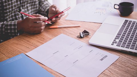 A CV and other documents laid out next to a laptop. 