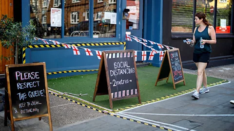 Getty Images A woman walks past a restaurant with social distancing markings in Portobello Market in London on June 1 following the easing of lockdown restrictions (Credit: Getty Images)