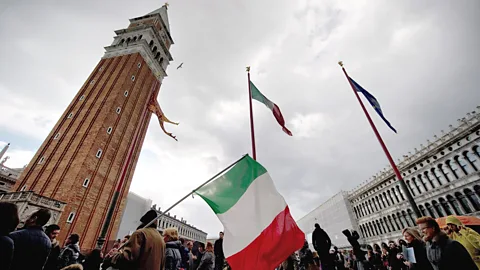 Getty Images Flags fly in Venice during a one-off holiday in Italy in 2011. It was found to have a positive economic impact – unlike proposed holidays in other countries (Credit: Getty Images)