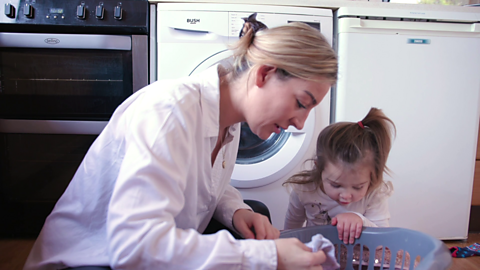 Mum and daughter looking into a laundry basket.