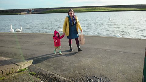 Mum and child walking by open water