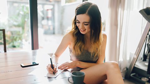 A teenage girl sat writing a letter