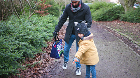 Dad and son walking while son points at ground