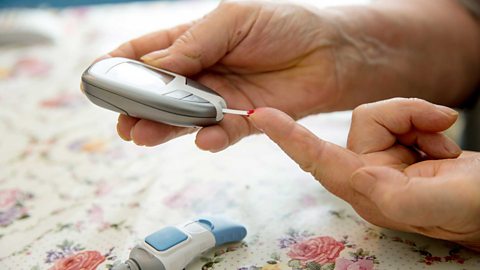 A close up of a pair of hands with a device to check insulin levels (diabetic)