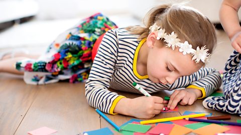 Young girl writes on colourful sticky notes.