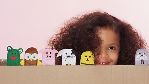 Young girl smiles with a collection of animal puppets.