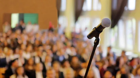 File image of a microphone in front of a blurred conference audience