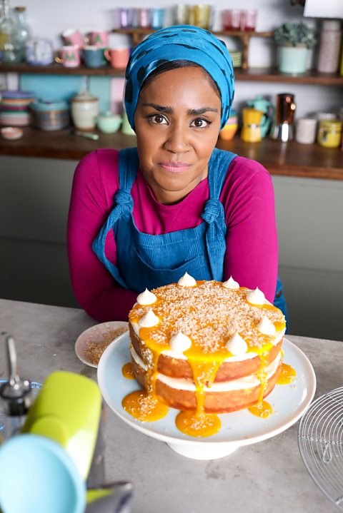 Nadiya poses with her Victoria sponge made with yogurt and filled with German butter cream, mango and toasted coconut 