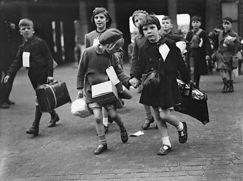 Children carrying their belonging to the train whilst being evacuated to the countryside in 1944.