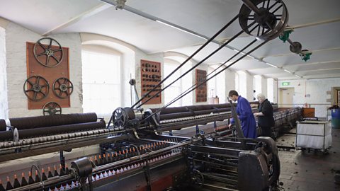 A large cotton spinning machine inside New Lanark mill, where many people worked side by side.