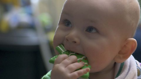 A baby boy chewing on a teething toy.