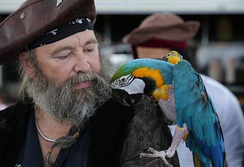 A participant dressed as a pirate looks at his parrot