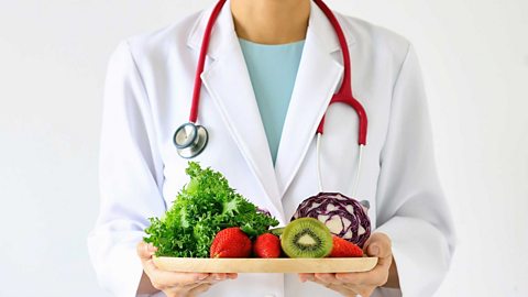 A doctor holding a plate of fruit and veg 