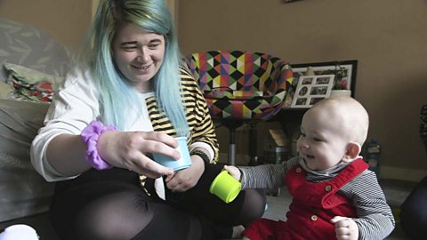 A mum and her little boy playing with cups.