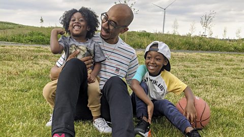 Robert sat in a field with his 2 sons.