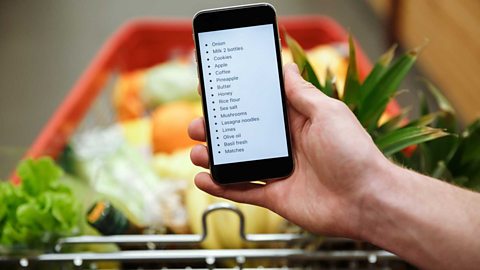 Before you do your shop A person looks at their shopping list while pushing a trolley in the supermarket