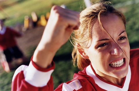 Young female soccer player cheering, displaying cute aggression through clenched teeth