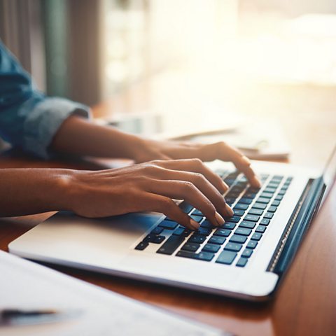 A young person typing at a laptop. 