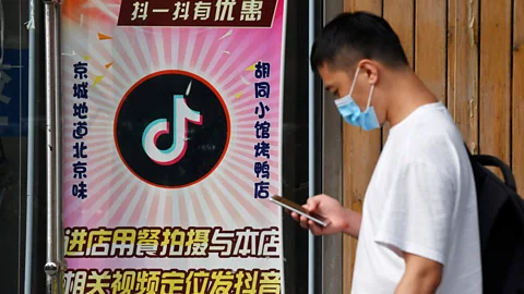 Greg Baker/Getty Images A man walks past a Beijing restaurant which offers a discount to anyone who posts videos on TikTok (Credit: Greg Baker/Getty Images)