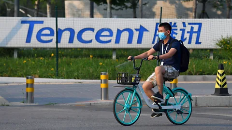 Greg Baker/Getty Images A man cycles past Tencent, the parent company of Chinese social media giant WeChat (Credit: Greg Baker/Getty Images)