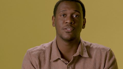 Abubakar Salim wearing a pink shirt in front of a yellow background.