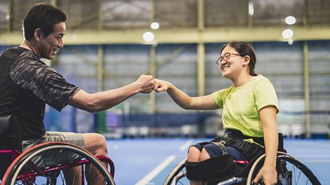 Disabled female athlete doing a fist bump with her coach during playing wheelchair tennis