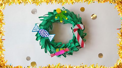 A Christmas wreath with drawings of different kinds of sweets decorating it.