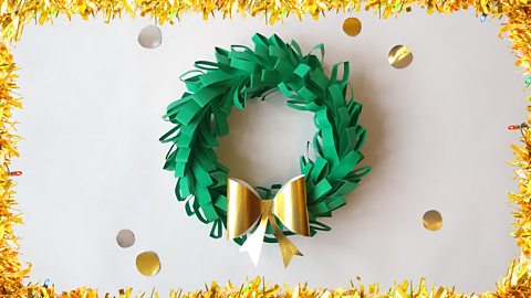 A green Christmas wreath with a gold bow on it.