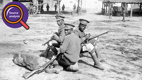 Three BWIR servicemen sat on the ground with their rifles. 