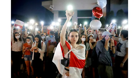 Kacper Pempel/Reuters A demonstrator holds up her phone during a march after the disputed presidential election in Belarus, August 2020 (Credit: Kacper Pempel/Reuters)