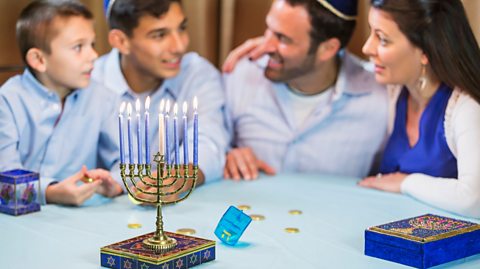 A family of four celebrate Hannukah with a dreidel and Hanukkiah
