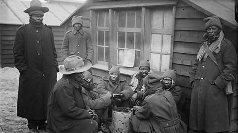 Members of the SANLC wearing multiple layers, gathered around a fire in camp.