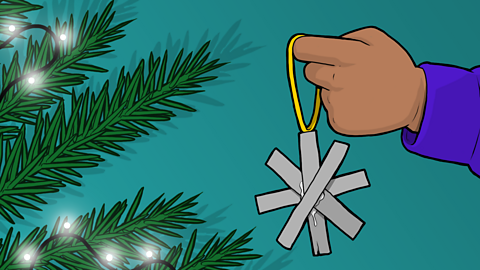 An illustration of a child's hand hanging a cardboard snowflake on a Christmas tree.