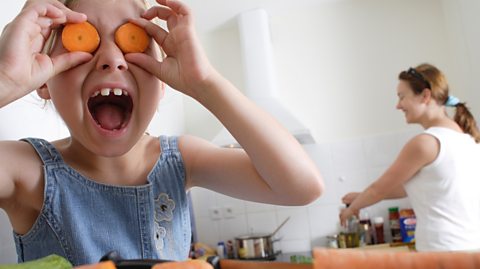 A girl holding carrots in front of her eyes