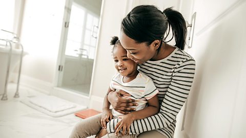 A mum and her toddler daughter in the bathroom together.