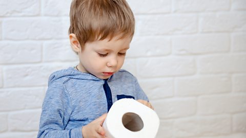 A little boy holding a loo roll.