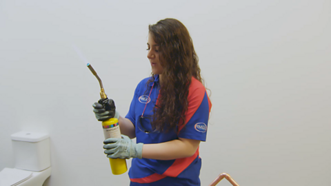 Louisa is standing up ready to weld a pipe
