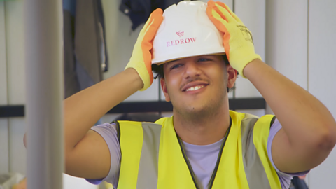 Sharif grabing his PPE hat with despair.