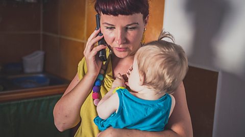 Worried mum on phone while holding her child.