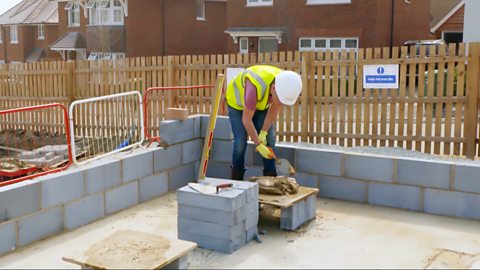 Louis is preparing mortar before layering bricks.