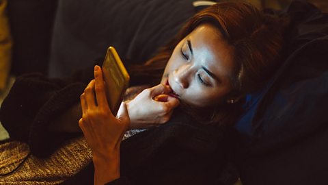 A woman looking at her phone at night.