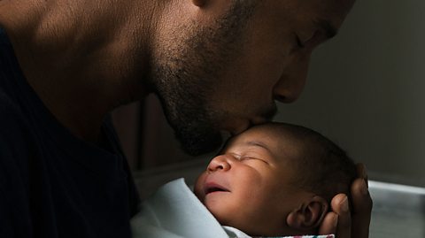 A dad kissing his baby's head.