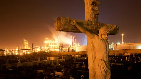 Alamy A graveyard in Louisiana with a chemical plant on the horizon (Credit: Alamy)